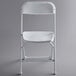 A white Lancaster Table & Seating folding chair with metal legs.