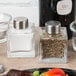 American Metalcraft ribbed square glass salt and pepper shakers with metal lids on a table.