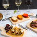 American Metalcraft Olive Wood Cheese Paper on a table with food and wine.