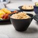 An American Metalcraft black porcelain bowl filled with food on a table.