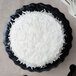 A white cake on a black Enjay cake circle with a knife on a white background.