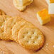 A group of Nabisco Ritz crackers on a wooden surface with cheese.
