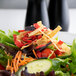 A salad with Fresh Gourmet tri-color tortilla strips, vegetables, and fruit on a table.