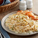 A plate of pasta with shrimp and Alfredo sauce on a table.