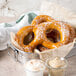 A metal tray of Big Apple Jumbo Soft Pretzels with a bowl of dipping sauce.