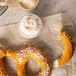A Big Apple jumbo soft pretzel with white sprinkles on a table.