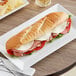 A sandwich on a plate with Amoroso's sliced hoagie roll.
