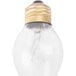 A close up of a 60 watt shatterproof light bulb with a gold metal base and a wire.