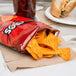 A bag of Doritos Nacho Cheese tortilla chips on a table next to a sandwich.
