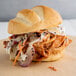 A pulled chicken sandwich with slaw and pickles.