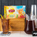 A case of Lipton iced tea filter bags on a table with a pitcher of iced tea.