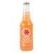 A close up of a glass bottle of Izze Sparkling Grapefruit Juice with orange liquid inside.