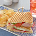A Bakery de France Ciabatta Panini roll sandwich with ham, cheese and tomatoes on a plate.