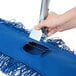 A hand holding a metal handle with a blue Lavex dust mop attached.