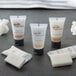 A group of small white Novo Essentials Hotel and Motel Shampoo bottles.