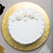 A white cake with frosting on a gold Enjay round cake drum.