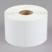 A white roll of paper with a roll of white labels.