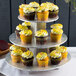A three tiered Enjay disposable silver cupcake stand holding cupcakes with yellow frosting and sprinkles.