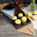 A black Enjay quad cupcake tulip box with cupcakes on a table.