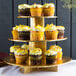 An Enjay gold cupcake stand with yellow frosted cupcakes and sprinkles.