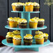 An Enjay 3-tier blue cupcake stand holding cupcakes on a table.