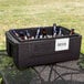 A Metro Mightylite food pan carrier with a red lid filled with beer bottles on a table.