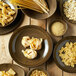 A group of Oneida Rustic porcelain chestnut dishes filled with pasta on a wood table.