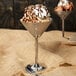 Two Tablecraft stainless steel martini glasses filled with ice cream and chocolate syrup.