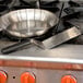 A pan and Mercer Culinary square edge turner on a stove.