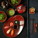 A table with Oneida Rustic Crimson bowls filled with green and liquid food.