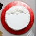 A white cake with frosting on a red Enjay round cake drum.