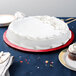A white cake on a red Enjay round cake drum on a table.