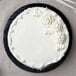 A white cake with white frosting on a black Enjay round cake drum.