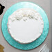 A white cake with white frosting and flowers on a blue Enjay cake drum.