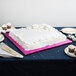 A white cake on a pink Enjay square cake board.