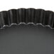 A black round Matfer Bourgeat non-stick fluted cake and tart pan with a wavy edge.