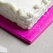 A white cake with frosting on a pink Enjay 1/2 sheet cake board.