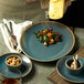 A plate of food on a wooden table with a Oneida Terra Verde Dusk porcelain coupe plate.