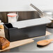 A black rectangular Matfer Bourgeat bread loaf pan with a lid open and a loaf of bread inside.