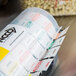 A National Checking Company day of the week label dispenser with 7 rolls of labels in a plastic container.