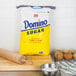 A bag of Domino Pure Cane Granulated Sugar next to muffins.