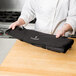 A chef holding a black Victorinox tri-fold knife roll.