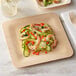 A Bamboo by EcoChoice square plate with shrimp and vegetables on a table.