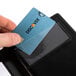 A hand holding a credit card in a black guest check presenter with a credit card pocket.