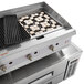 A stainless steel Cooking Performance Group lava briquette charbroiler over a refrigerated chef base.