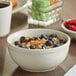 An Acopa ivory stoneware bowl filled with oatmeal and blueberries.