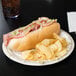 A Solo Symphony paper plate with a sub sandwich, chips, and a hot dog with lettuce, tomato, and bacon.