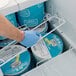 A hand in a blue glove placing an Avantco shelf in a commercial freezer.