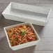 An American Metalcraft white rectangular porcelain bowl with pasta, tomatoes, and basil.