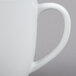 A close-up of a white Tuxton Milano china mug with a handle.